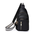 Sac à bandoulière noir en cuir avec fermeture éclair dorée et sangle à motif géométrique blanc et noir, idéal pour un style urbain et moderne.