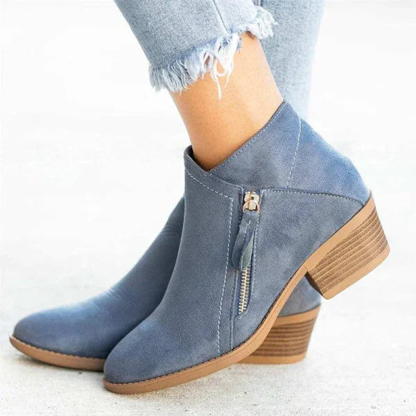 Bottines en daim bleu avec talon en bois, fermeture éclair latérale, portées avec un jean déchiré. Chaussures tendance automne-hiver pour femmes.