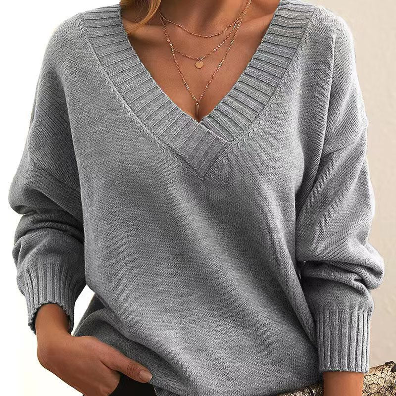 Femme portant un pull gris à col en V, manches longues, avec col côtelé. Mode automne-hiver, style décontracté et élégant.