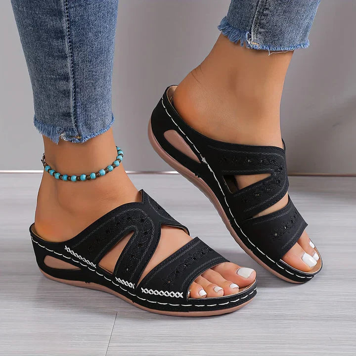 Sandales noires à talons compensés, portées avec un jean déchiré et un bracelet de cheville turquoise. Mode estivale, chaussures confortables.