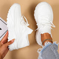 Chaussures de sport blanches modernes sur fond beige, portées avec un jean déchiré. Sneakers tendance, confortables et élégantes pour un look décontracté.