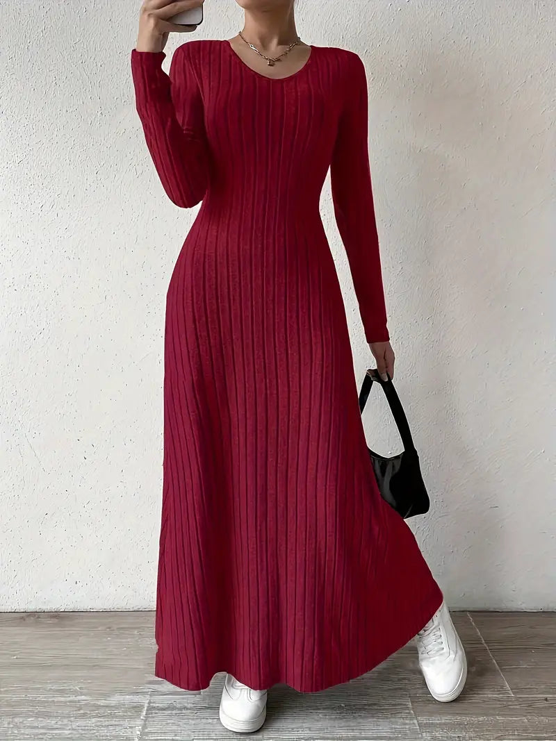Robe longue rouge à manches longues, tricotée, portée avec des baskets blanches et un sac noir. Mode féminine élégante et décontractée.