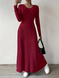 Robe longue rouge à manches longues, tricotée, portée avec des baskets blanches et un sac noir. Mode féminine élégante et décontractée.