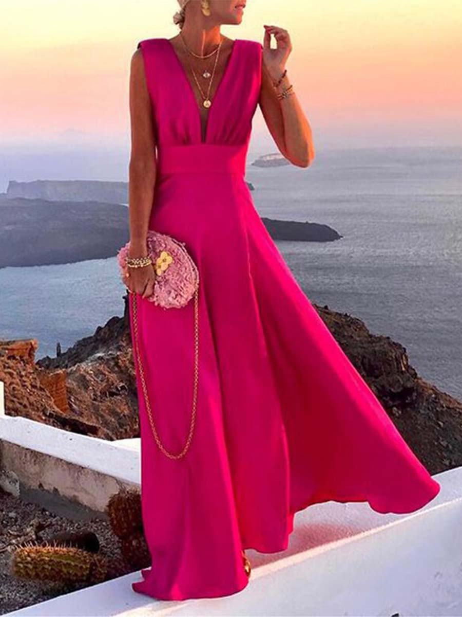Robe longue rose fuchsia élégante portée par une femme au coucher du soleil, avec sac à main assorti, vue sur mer en arrière-plan. Mode estivale chic.