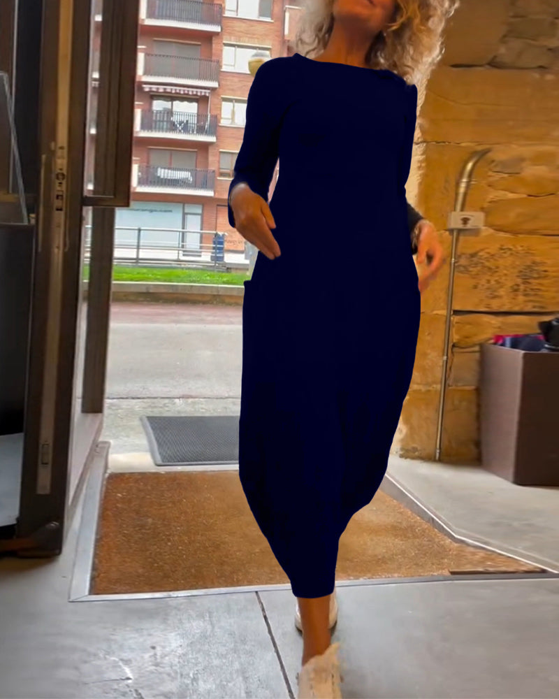 Femme en robe bleue élégante sortant d'un bâtiment moderne, chaussée de baskets blanches. Mode urbaine, style décontracté chic.