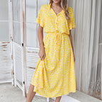 Robe d'été jaune à pois blancs, manches courtes, col chemise, ceinture à nouer, portée par une femme devant un paravent en bois.