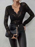 Femme portant un haut en dentelle noire avec un décolleté en V, pantalon en cuir noir et sac à main noir à chaîne dorée, mode élégante et chic.