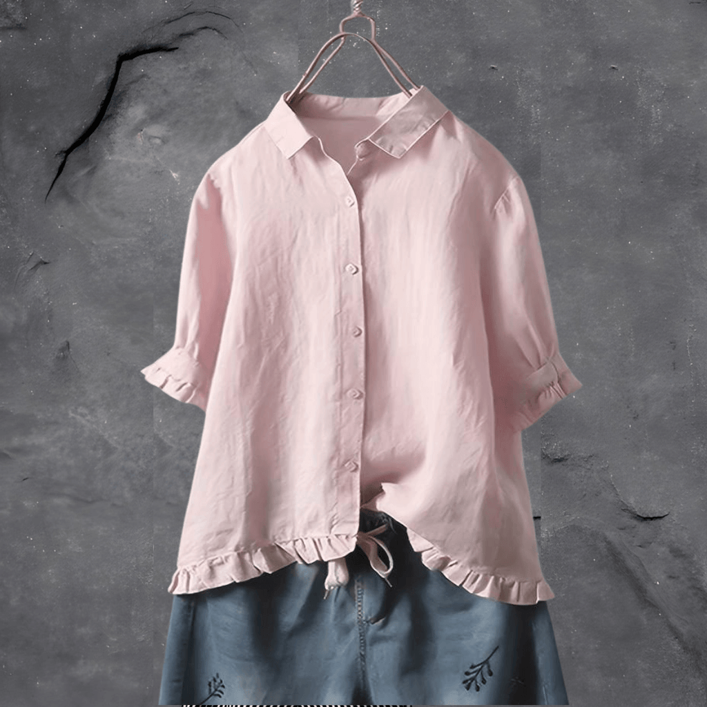 Chemisier rose en lin sur cintre, manches retroussées, col classique, fond gris texturé. Mode féminine, vêtement élégant, style décontracté.