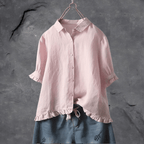 Chemisier rose en lin sur cintre, manches retroussées, col classique, fond gris texturé. Mode féminine, vêtement élégant, style décontracté.