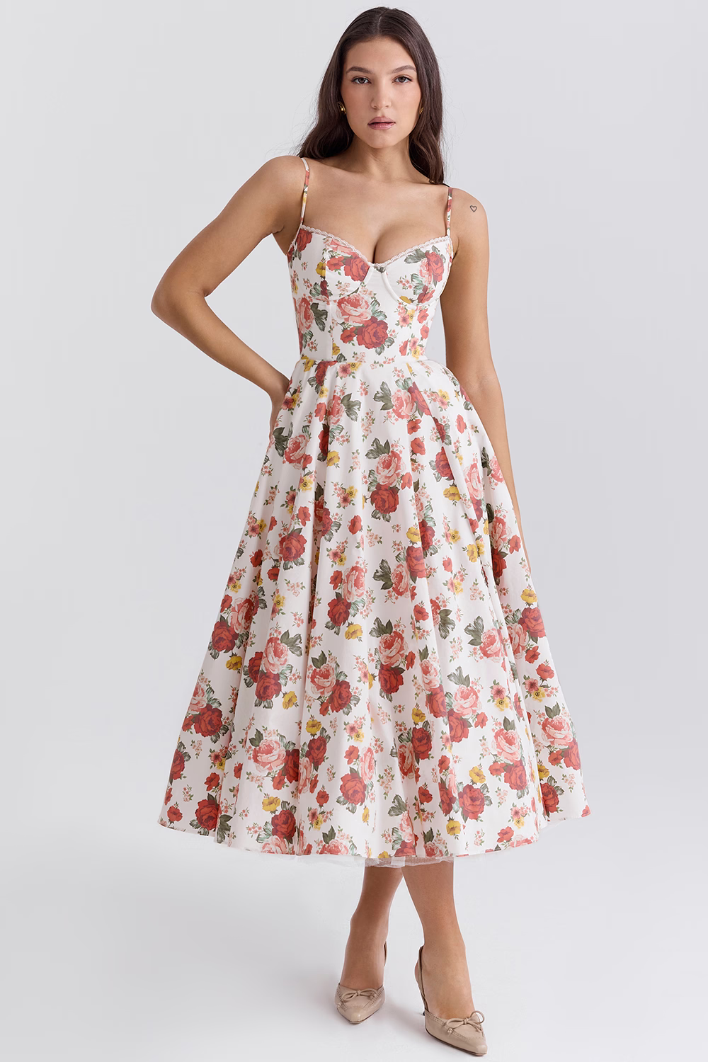 Robe longue à fleurs rouges et roses, décolleté en cœur, bretelles fines, portée par une femme. Mode élégante, tenue estivale chic.