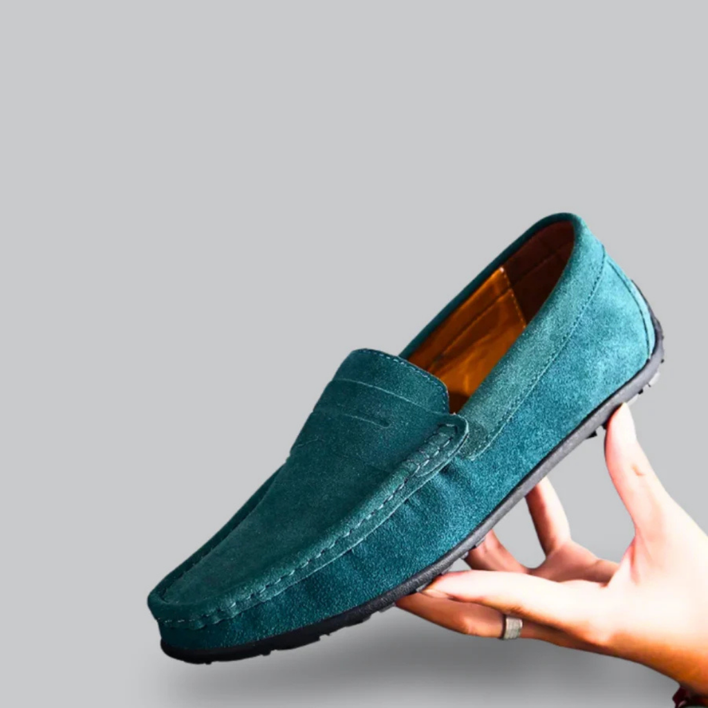 Mocassin en daim vert pour homme, élégant et moderne, tenu en main. Chaussure décontractée avec semelle noire, idéale pour un style chic et confortable.
