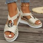 Sandales compensées beiges avec semelle en corde, ornées d'un anneau métallique argenté, portées avec un jean. Mode estivale, chaussures tendance.