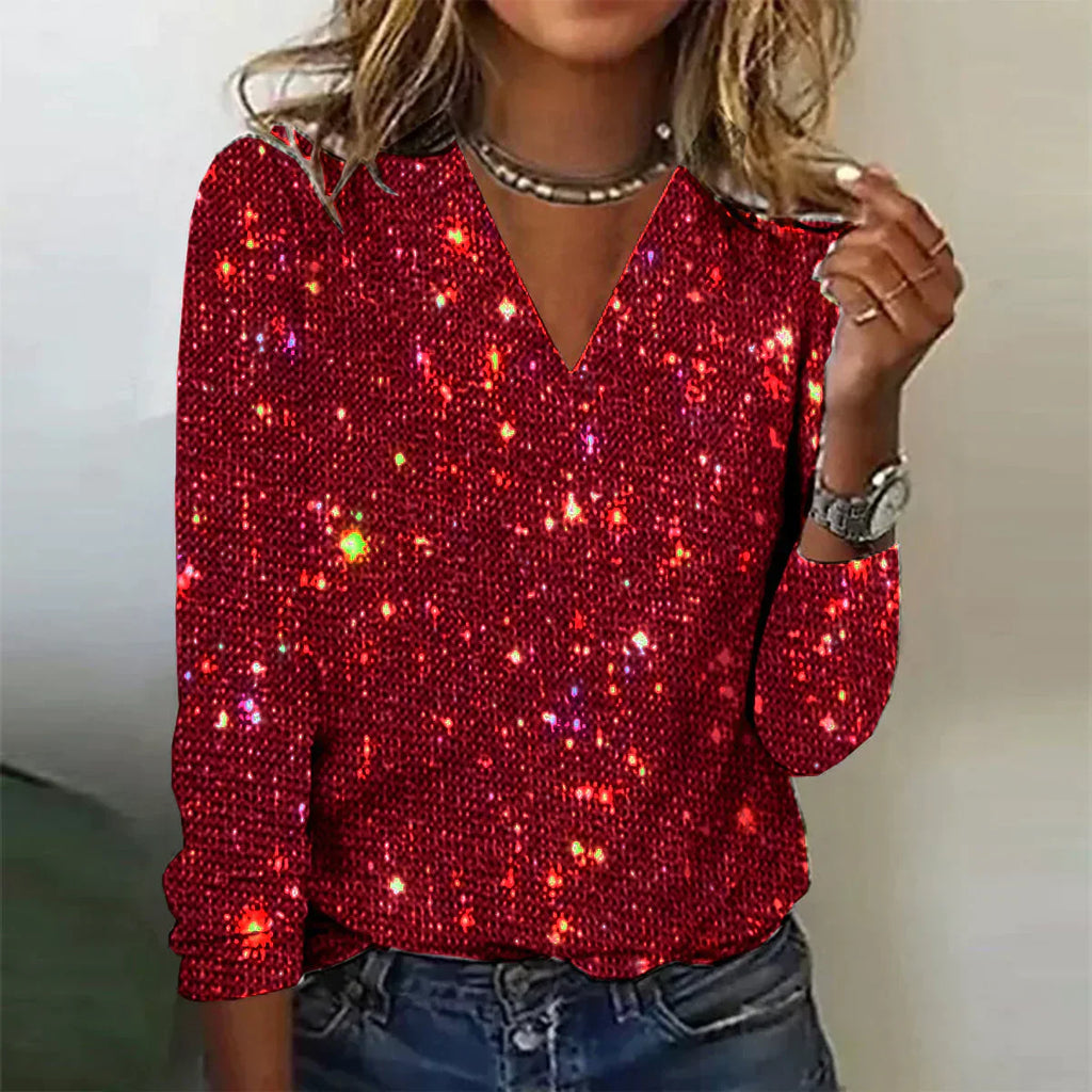 Femme portant un pull rouge à paillettes scintillantes, manches longues, col en V, avec un collier et une montre argentée. Mode tendance et élégante.
