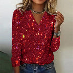 Femme portant un pull rouge à paillettes scintillantes, manches longues, col en V, avec un collier et une montre argentée. Mode tendance et élégante.