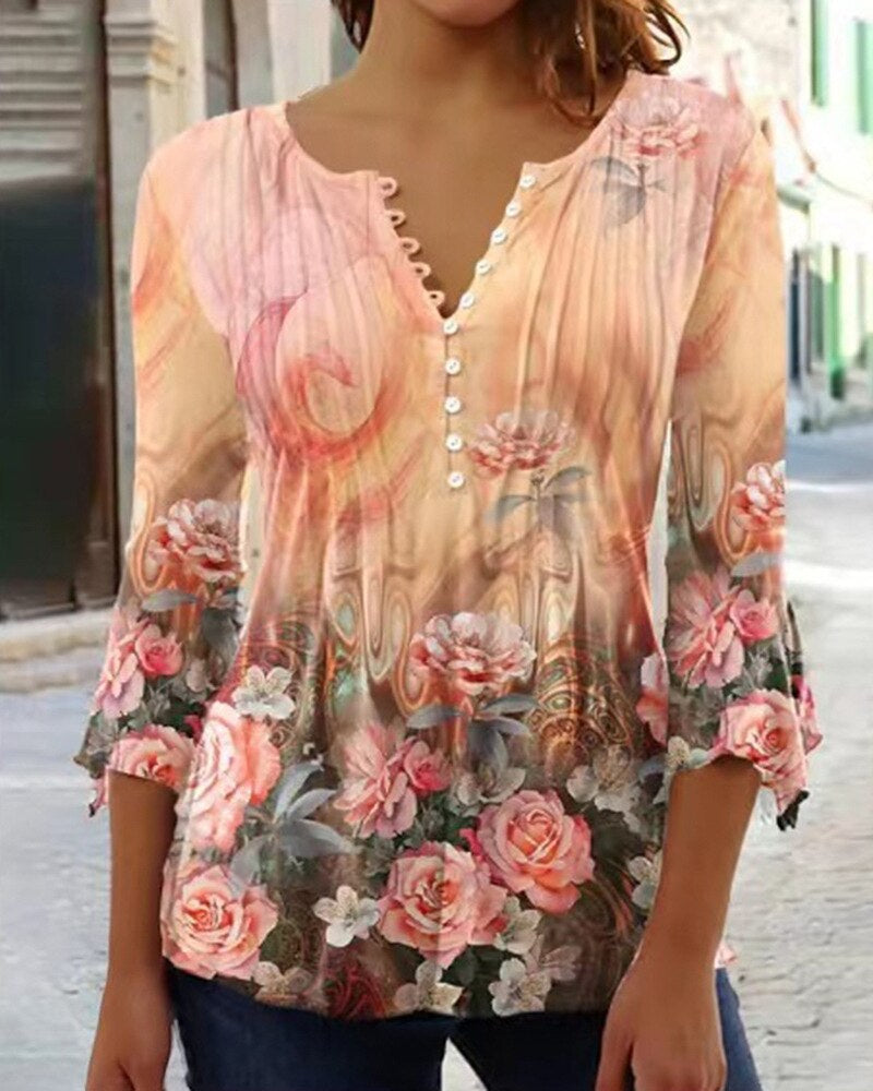 Blouse femme à manches longues, motif floral rose et beige, col en V avec boutons, style bohème chic, rue urbaine en arrière-plan.