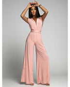 Femme portant une combinaison rose élégante, sans manches, avec jambes larges, posant sur fond neutre. Mode féminine, tenue chic, style moderne.