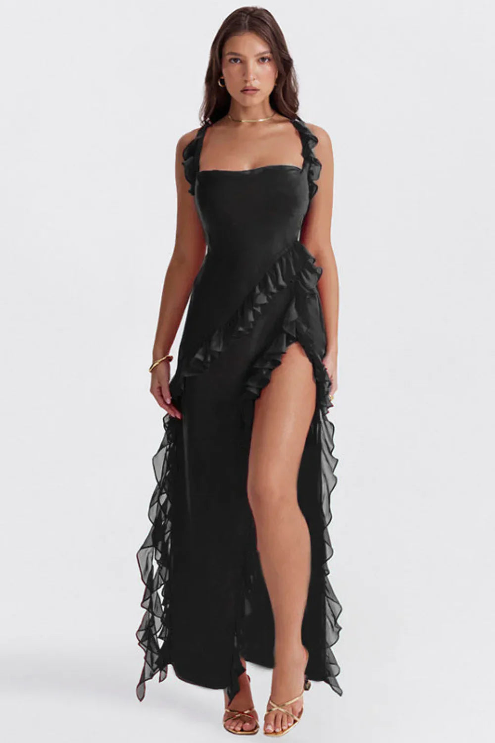 Robe noire élégante avec volants, fente haute, portée par une femme. Mode féminine, tenue de soirée chic, style glamour.