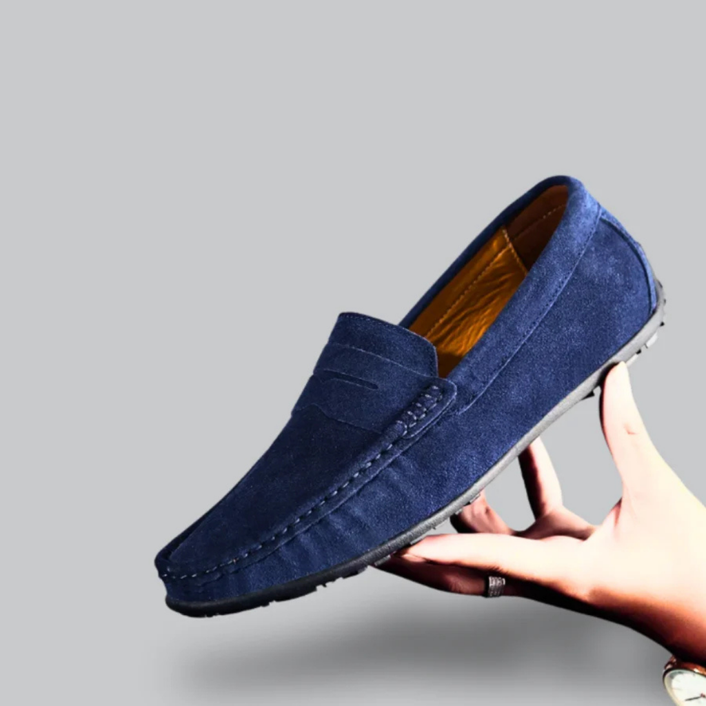 Mocassin bleu en daim pour homme, élégant et confortable, tenu par une main. Chaussure mode, semelle antidérapante, style décontracté.