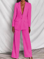 Costume femme rose vif, veste à un bouton, pantalon large, élégant et moderne, mode féminine, tenue professionnelle chic.