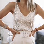 Femme portant un débardeur à paillettes argentées, ceinture blanche et bracelet élégant. Mode chic, tenue de soirée glamour.