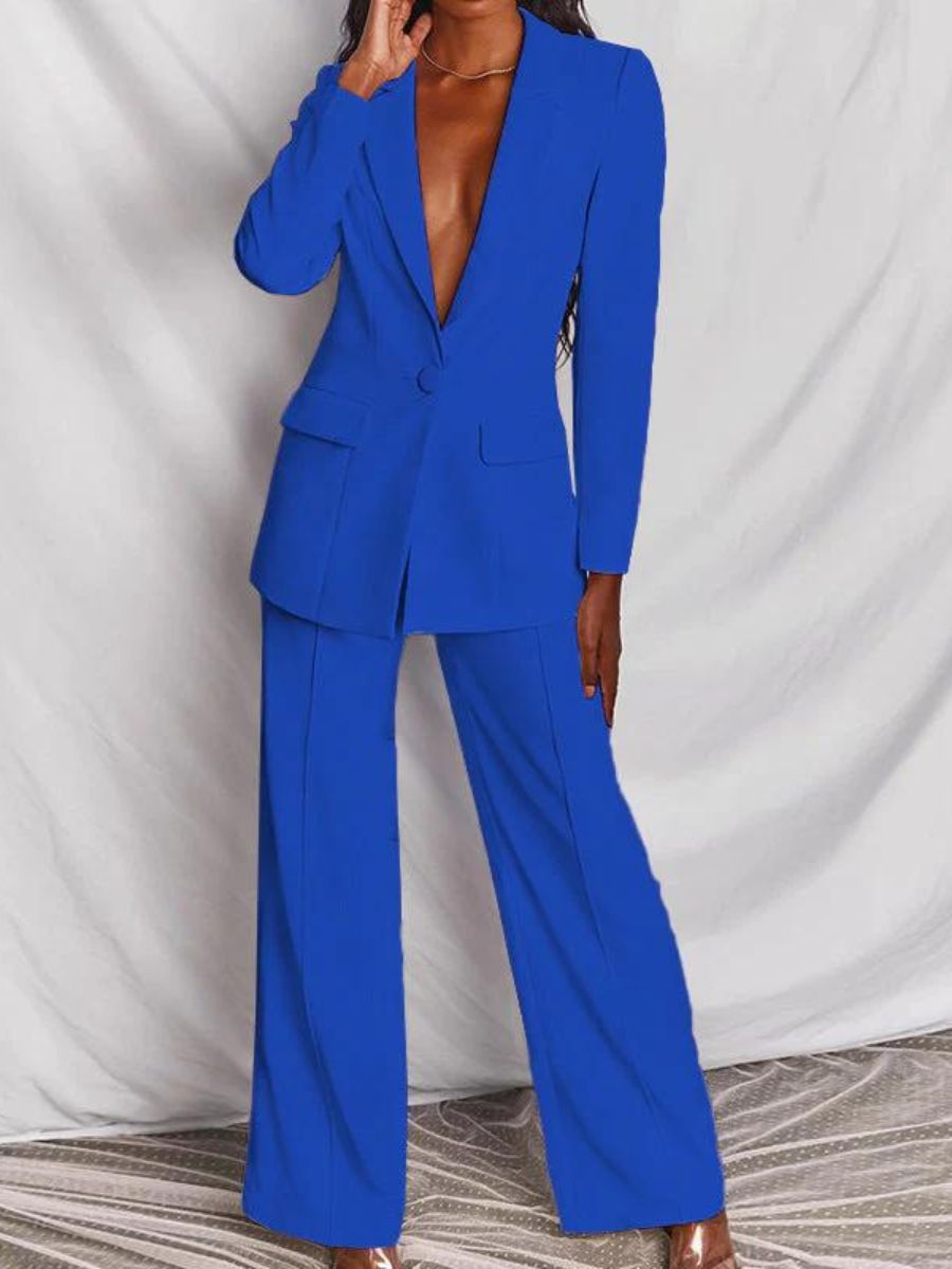 Femme portant un costume bleu vif, veste et pantalon élégants, posant devant un fond neutre. Mode féminine, tenue professionnelle chic.
