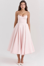 Robe rose élégante mi-longue avec bretelles fines, corsage ajusté et jupe évasée, portée par une femme. Mode féminine chic et tendance.
