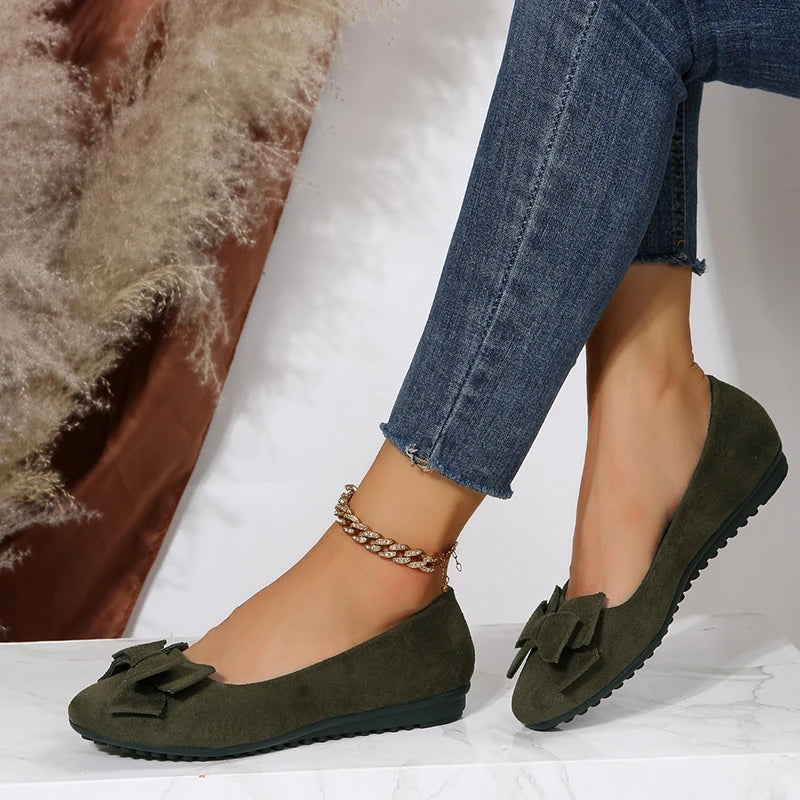 Ballerines vertes en daim avec nœud, portées avec un jean ajusté. Chaussures élégantes pour femme, tendance et confortables.