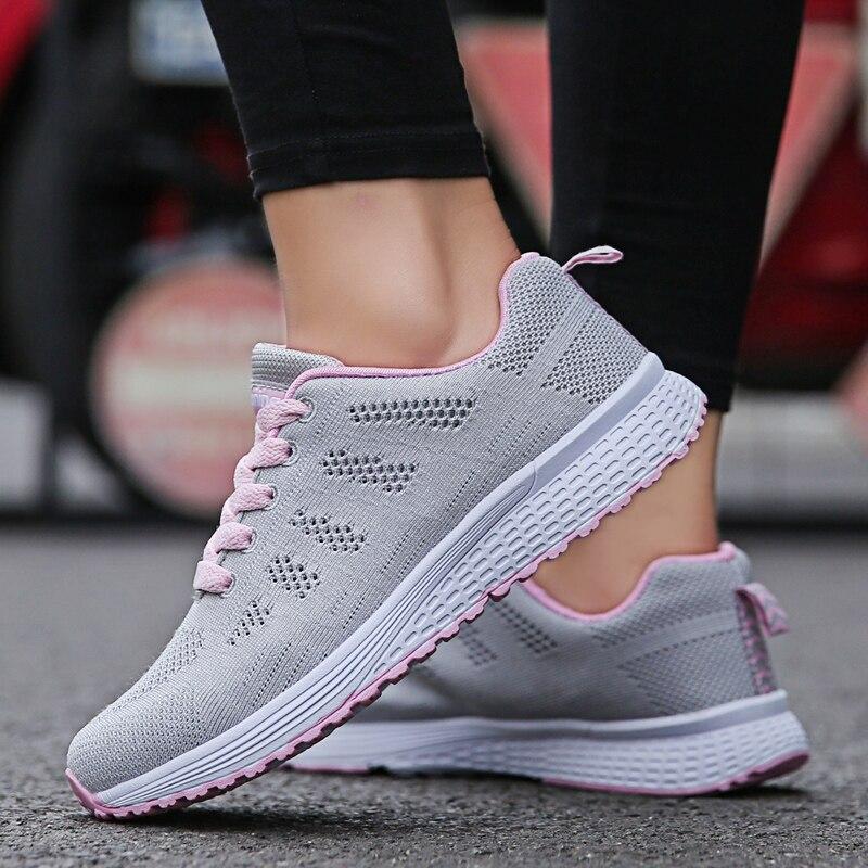 Chaussures de sport femme grises avec lacets roses, semelle blanche antidérapante, idéales pour la course et le fitness en extérieur.