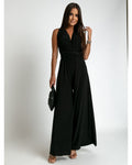 Femme portant une élégante combinaison noire sans manches, tenant un sac à main noir. Mode chic, tenue de soirée, style moderne.