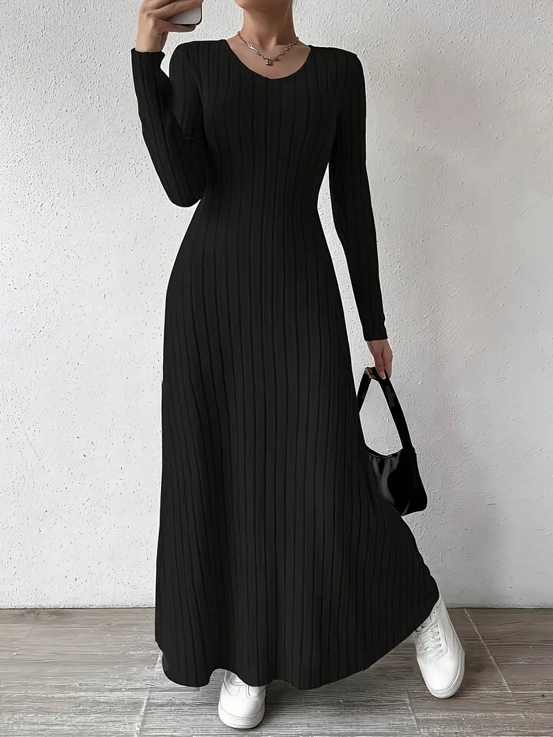 Robe longue noire côtelée, manches longues, portée avec des baskets blanches et un sac à main noir. Mode élégante et décontractée pour femme.