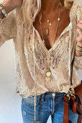 Blouse en dentelle beige élégante, col en V, portée avec colliers dorés superposés et jean décontracté. Mode féminine chic et tendance.
