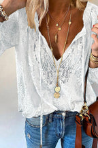 Femme portant un chemisier en dentelle blanche avec col en V, colliers dorés superposés, jean bleu décontracté et sac marron. Mode élégante et tendance.