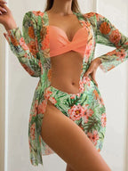 Femme en maillot de bain orange avec paréo floral tropical, pose élégante. Mode plage, style estival, tendance maillot 2023.