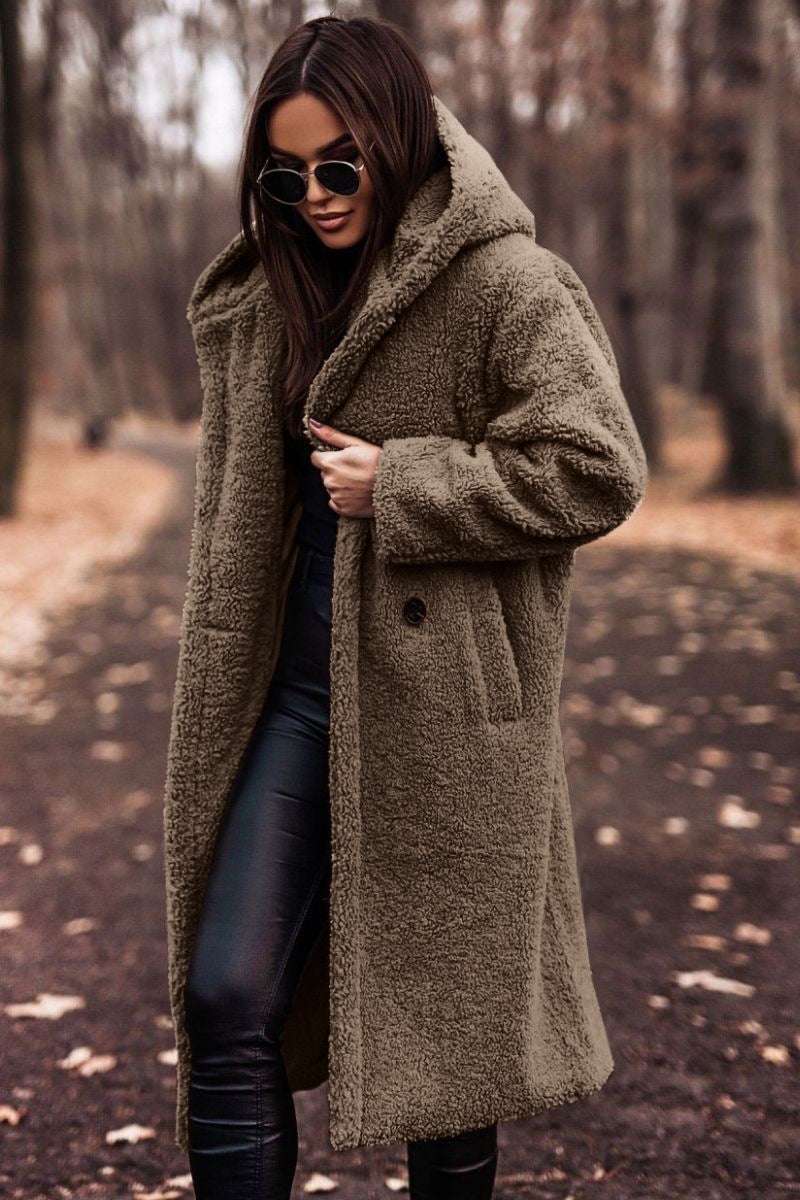 Femme portant un manteau en fausse fourrure marron, lunettes de soleil, dans un parc automnal. Mode hiver, style chic, promenade forêt.