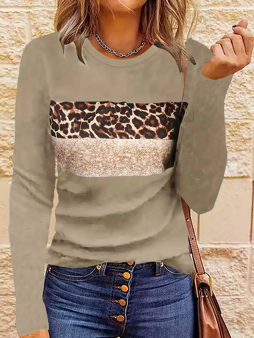Femme portant un pull beige à motif léopard et paillettes, avec un jean bleu à boutons. Mode automne, style décontracté chic.
