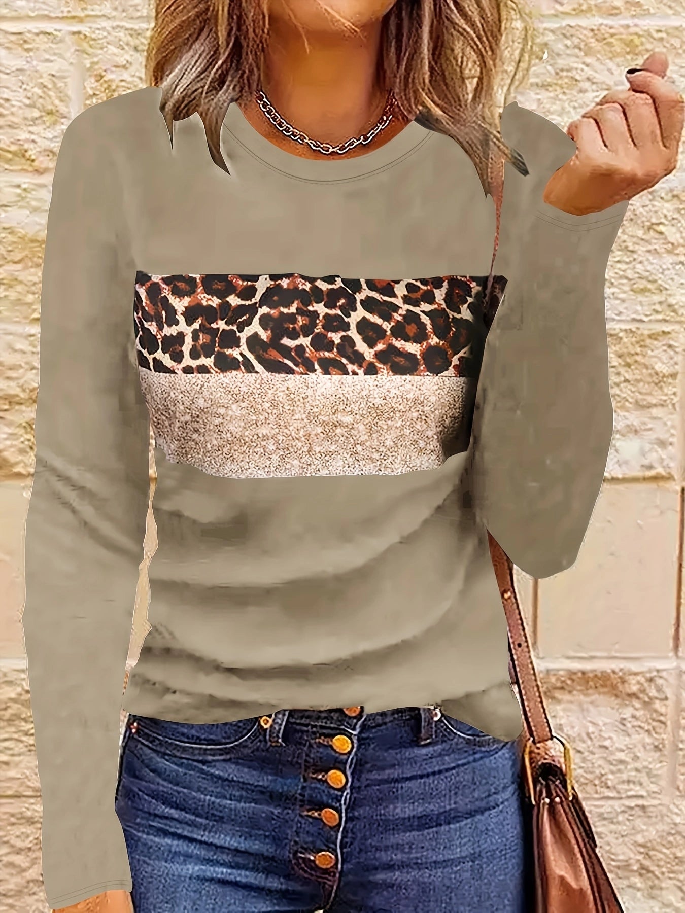 Femme portant un pull beige à motif léopard et paillettes, avec un jean bleu à boutons. Mode automne, style décontracté chic.