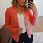 Femme portant un blazer corail élégant, chemise blanche et jean, prenant un selfie dans un miroir. Mode féminine, tenue chic et décontractée.