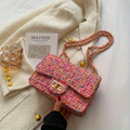 Sac à main en tweed multicolore avec chaîne dorée sur manteau blanc, livre "Matisse" et décorations dorées. Mode élégante et tendance.