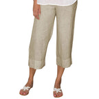 Pantalon en lin beige pour femme, coupe ample, longueur 7/8, porté avec des sandales blanches. Mode estivale décontractée et élégante.