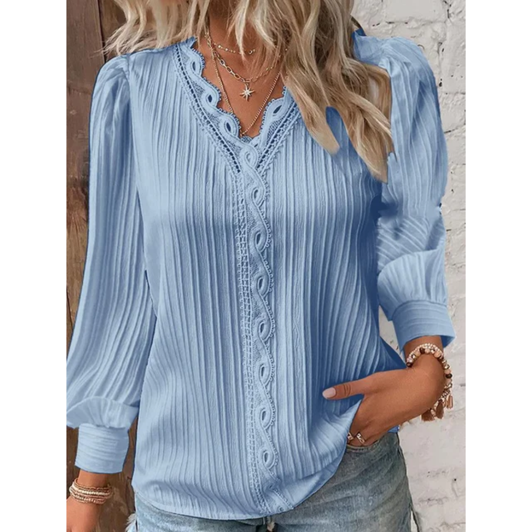 Blouse bleue plissée à manches longues avec dentelle, portée par une femme blonde. Mode féminine élégante, tenue décontractée chic.