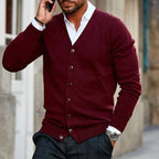 Homme portant un cardigan bordeaux élégant, chemise blanche, pantalon gris, parlant au téléphone. Mode masculine, style automne-hiver, tenue chic.