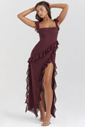 Femme portant une robe longue bordeaux à volants, élégante et chic, posant sur fond neutre. Mode féminine, tenue de soirée glamour.