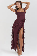 Femme portant une robe longue bordeaux à volants, élégante et chic, posant sur fond neutre. Mode féminine, tenue de soirée glamour.