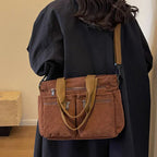 Sac à main en velours côtelé marron avec bandoulière, porté par une personne en manteau noir. Accessoire mode tendance, pratique et élégant.