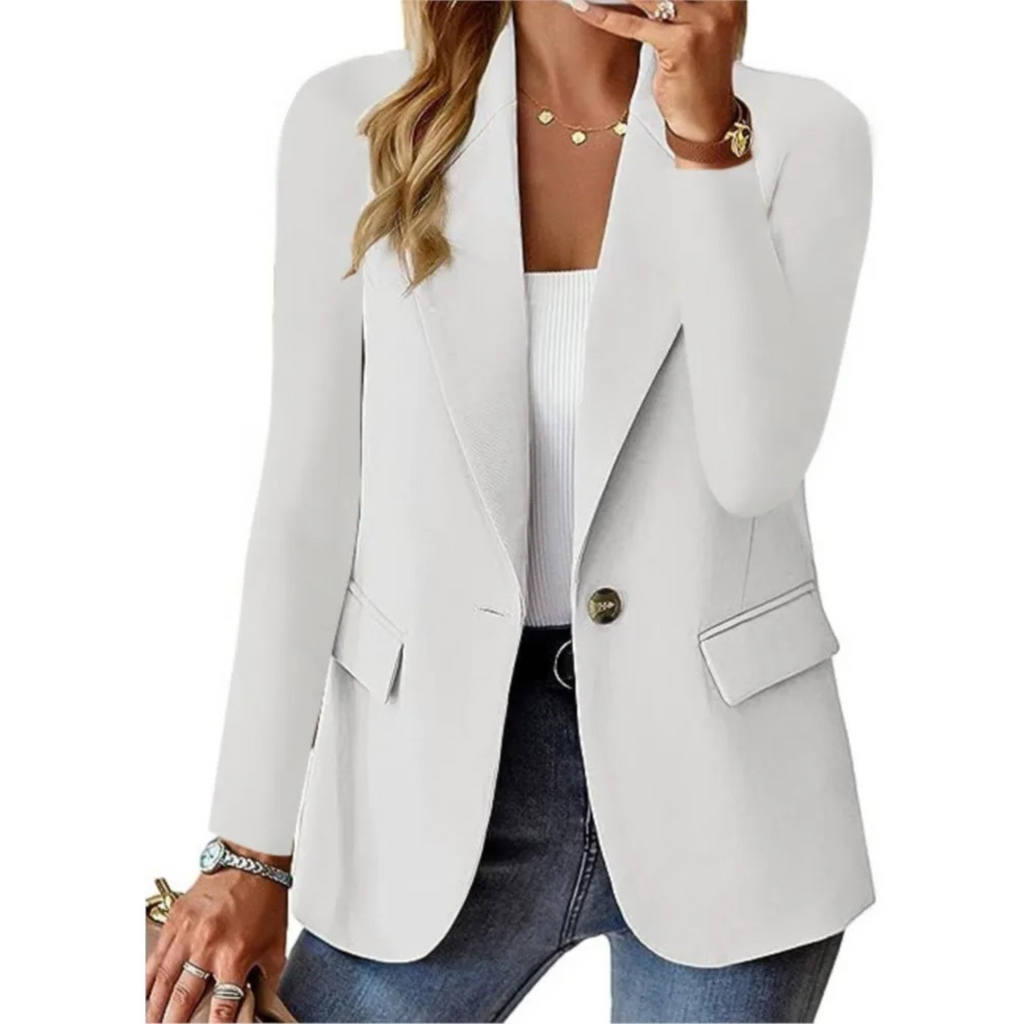 Femme portant un blazer blanc élégant, chemise blanche, jeans décontracté, montre dorée et collier, style chic et moderne pour bureau ou sortie.