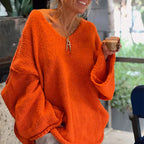 Femme souriante portant un pull oversize orange, tenant une tasse de café. Mode automne, confort, style décontracté.