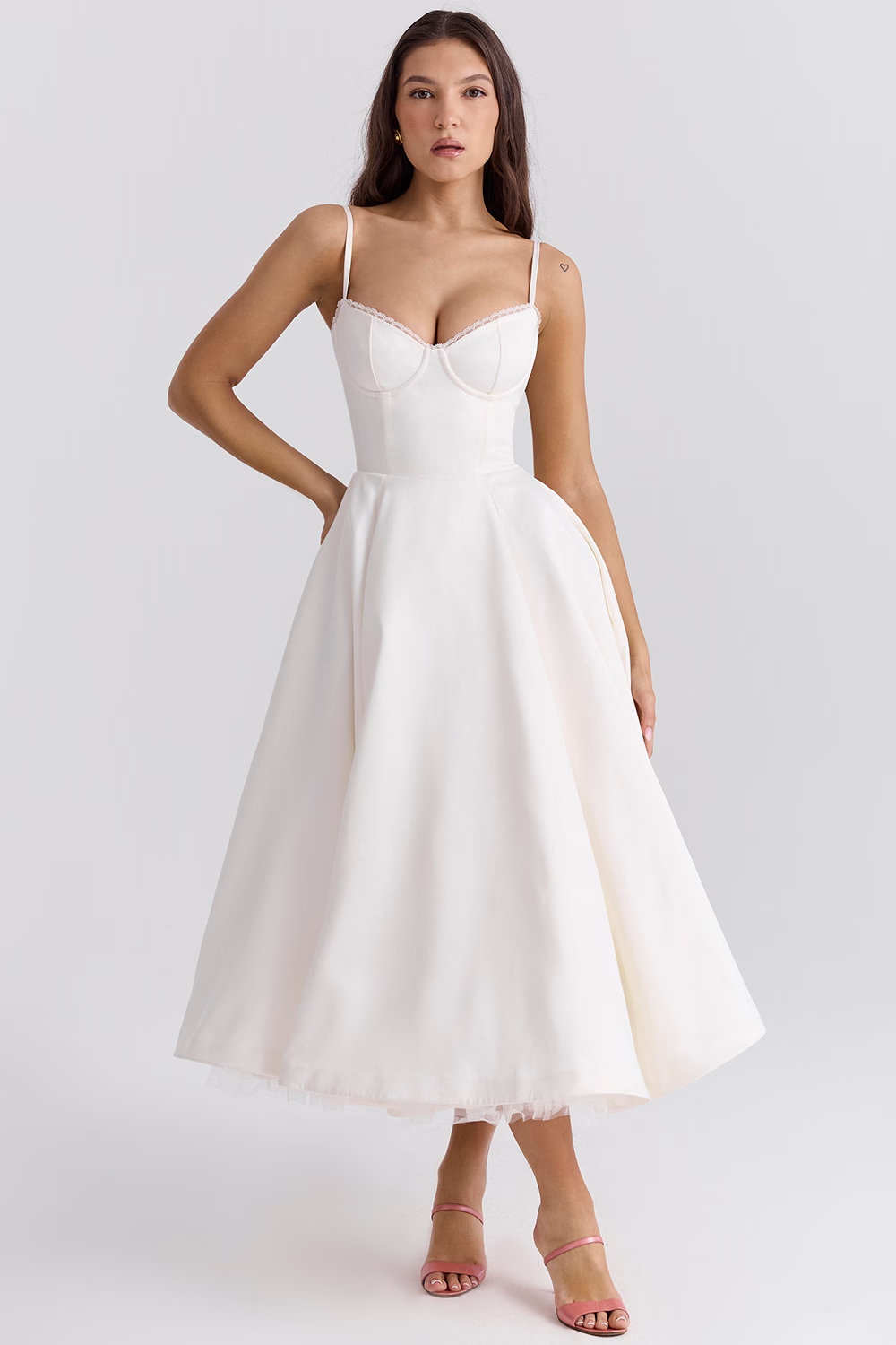 Robe blanche élégante mi-longue avec bretelles fines, décolleté en cœur, portée par une femme. Mode féminine, tenue de soirée chic.