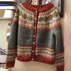 Gilet en laine tricoté à motifs nordiques, gris et rouge, avec boutons blancs. Vêtement d'hiver chaud et élégant, style scandinave.