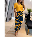 Femme en tenue élégante, chemisier jaune vif et pantalon bleu à motifs géométriques, posant dans un salon moderne. Mode féminine chic et tendance.