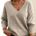 Femme portant un pull gris à col en V, manches longues, avec col côtelé. Style décontracté, mode automne-hiver, tendance féminine élégante.